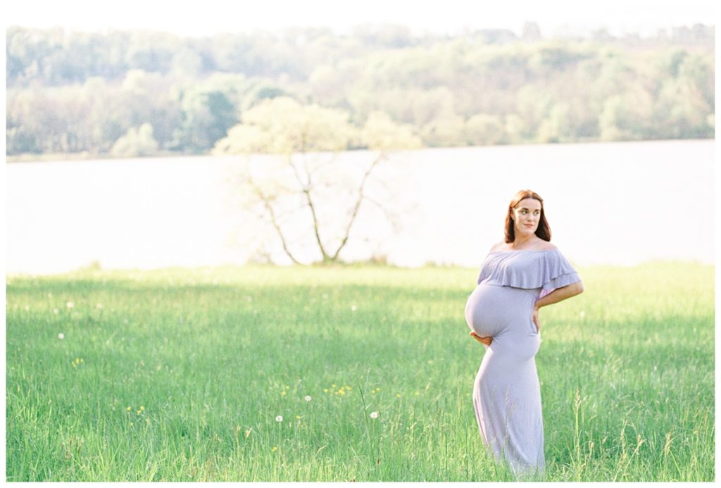 A Beautiful Maternity Session at Peace Valley Park | Doylestown, PA Photo of a woman at a maternity session in a field at Peace Valley Park wearing a lavender dress