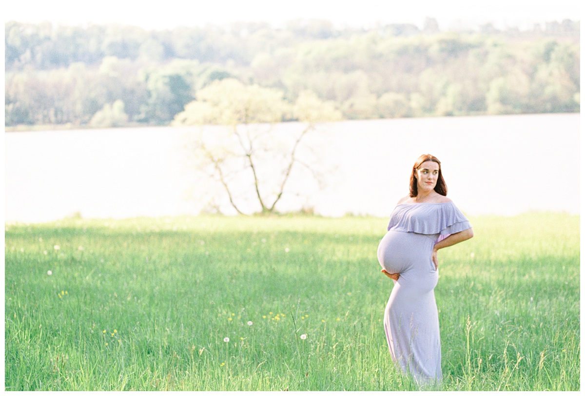 Photo of a woman at a maternity session in a field at Peace Valley Park wearing a lavender dress