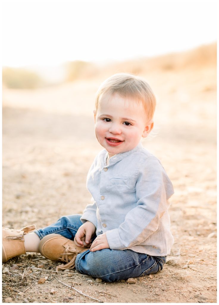 A little boy sitting down on the ground at the selected location for family photos
