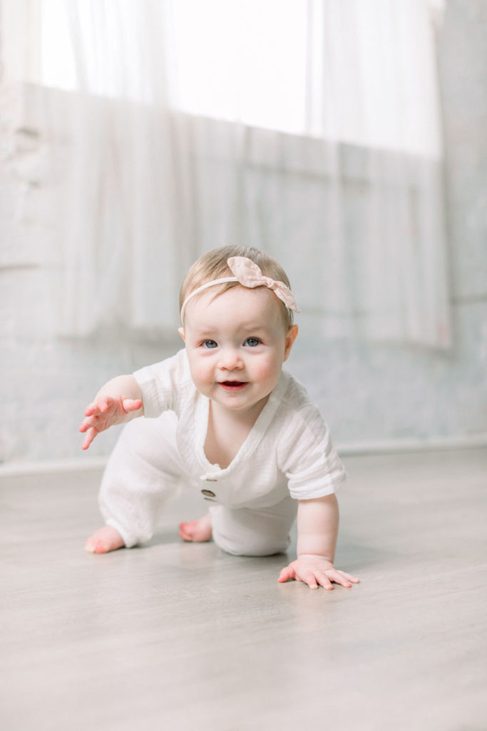 a mother wearing a pink dress and her daughter in a white romper during a studio motherhood session