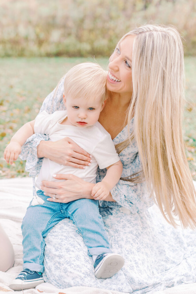 Choosing the Perfect Style Of Family and Newborn Photography For You Image of Mom, and little boy sitting on a blanket at a park. This is an example of lifestyle family and newborn photography