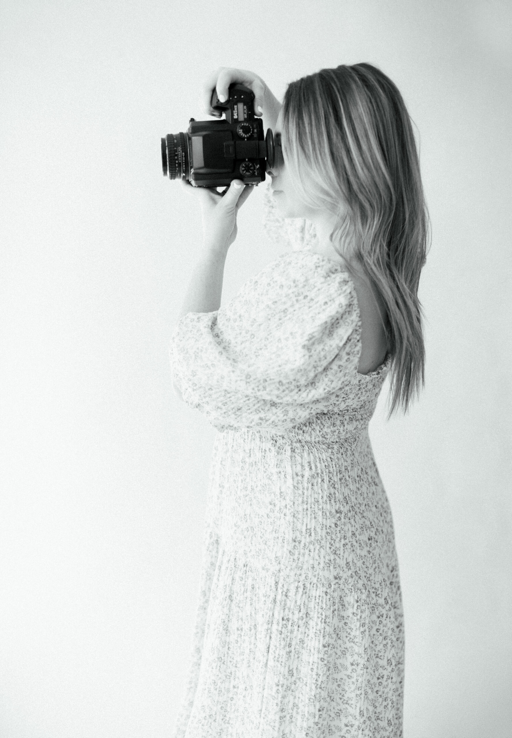 black and white photo of a new Jersey photographer holding a film camera up to her fave