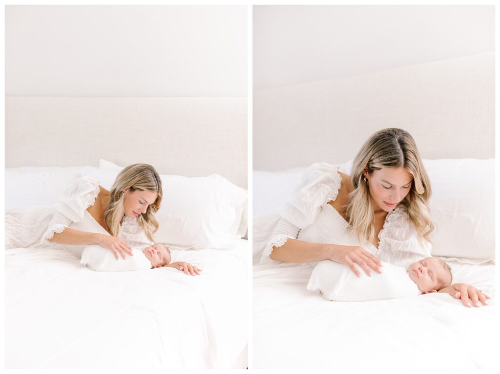 A mother in a white dress poses on the bed with her newborn daighter who is in a white swaddle during their in-home newborn session