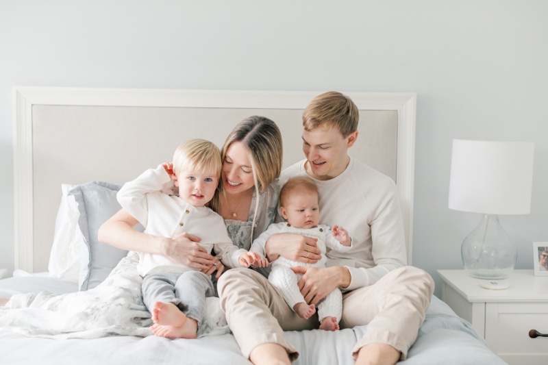 A family sitting on the bed and laughing together during Chatham, NJ Newborn photos
