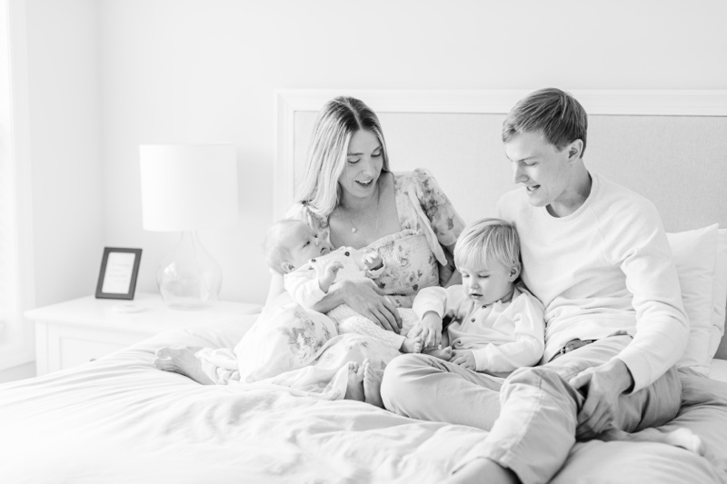A family sitting on the bed and laughing together during Chatham, NJ Newborn photos
