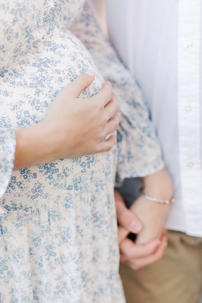 A closeup of hands on a pregnant belly during maternity photos at Loantanka Brook Reservation