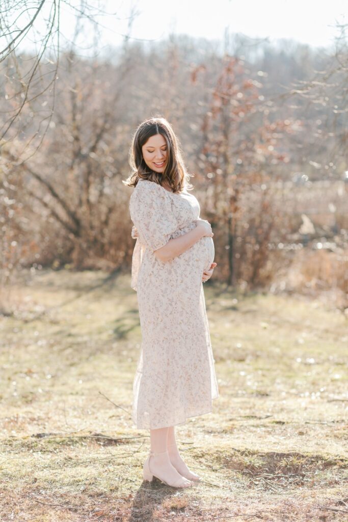 A pregnant woman poses during maternity photos at Loantanka Brook Reservation