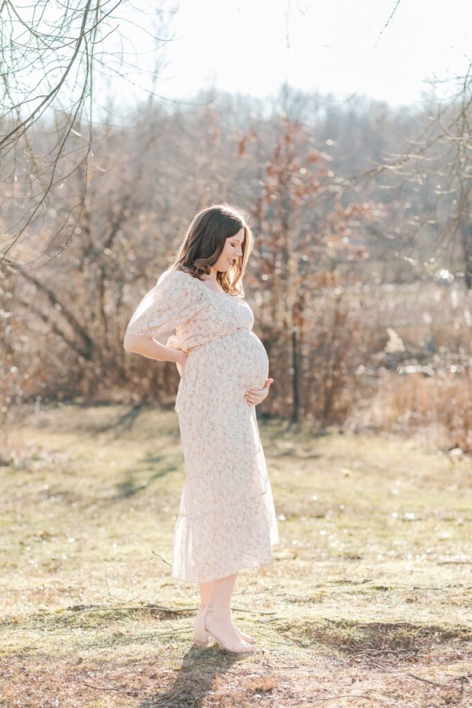 A pregnant woman poses during maternity photos at Loantanka Brook Reservation