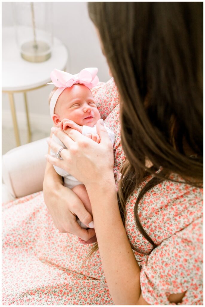 A mother looking down at her newborn baby girl during newborn photos at home