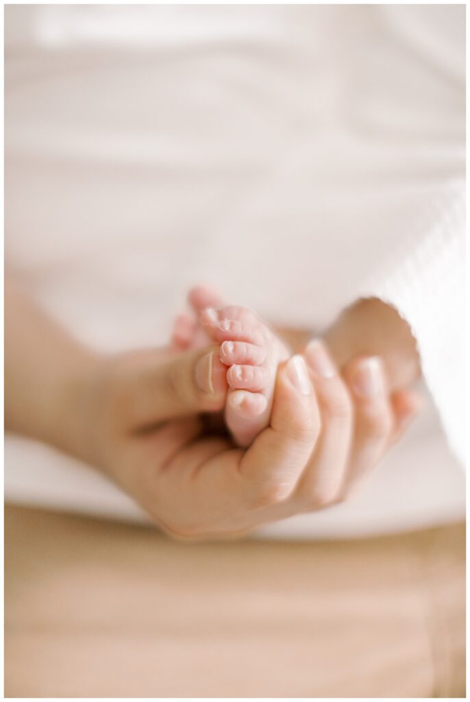 A new father holding his tiny newborn baby's foot in his hand during at home newborn photos