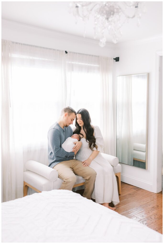 A couple holds their newborn baby during newborn photos at home