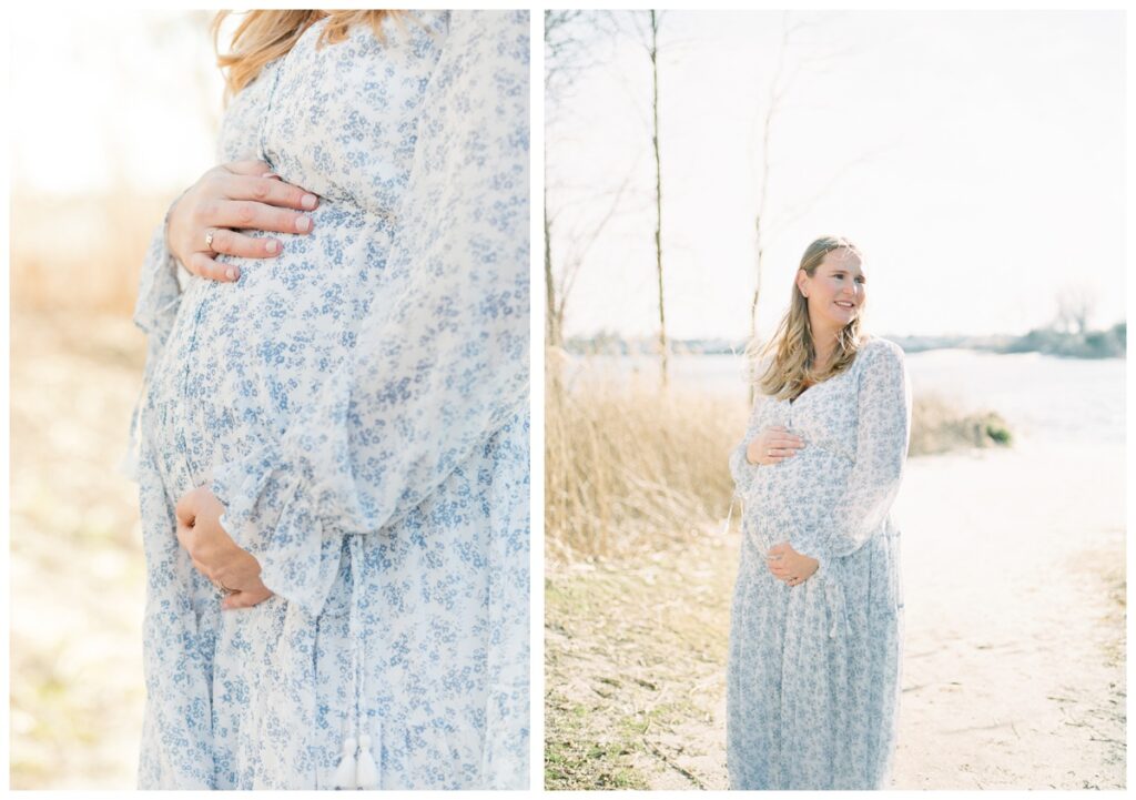 A woman wearing a long sleeve white dress with blue flowers poses during her beach maternity photos