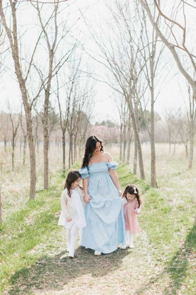 A woman wearing a blue dress walks with her two daughters during a Mommy and Me Photo Session.