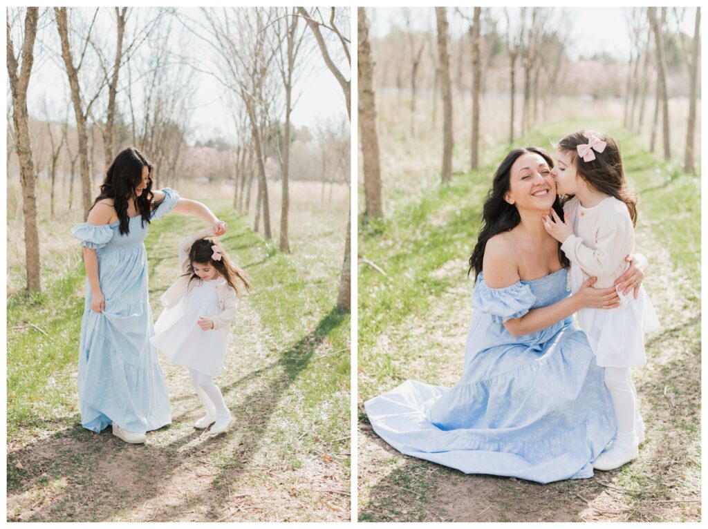 A mother wearing a blue dress twirls her daughter who is wearing a white dress during their Mommy + Me Photo session. 