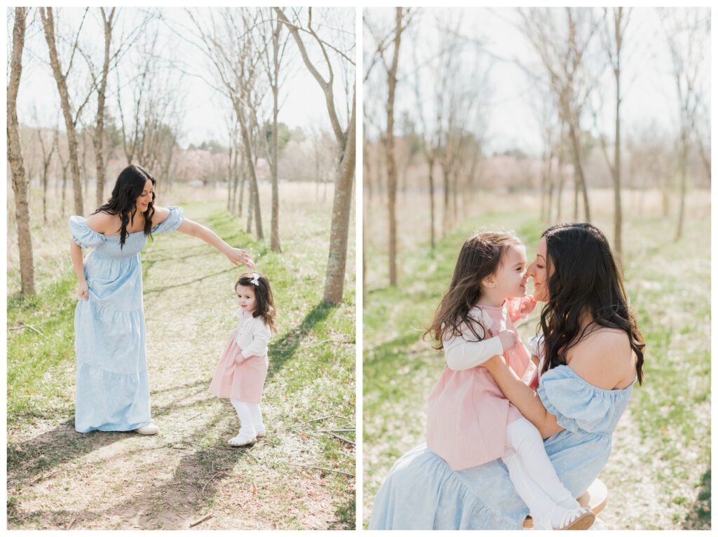 A woman in a blue dress holds her daughter who is wearing a pink dress.