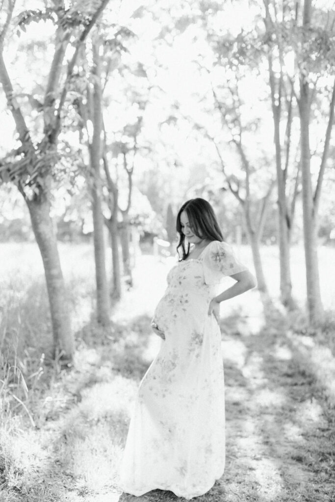 A pregnant woman stands under the trees during her outdoor maternity photos in New Jersey. 