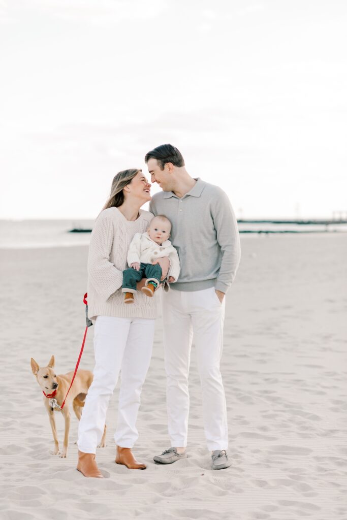 A family of three with their dog on the beach during winter family photos in NJ.