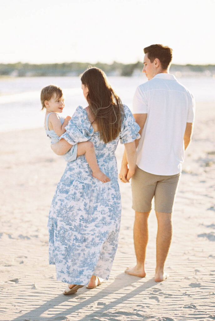 Mini Session, Half, or Full: Which Is Right for Your Family? (2026) Family walking barefoot along the sand at Fisherman's Cove, with their toddler smiling back over mom's shoulder