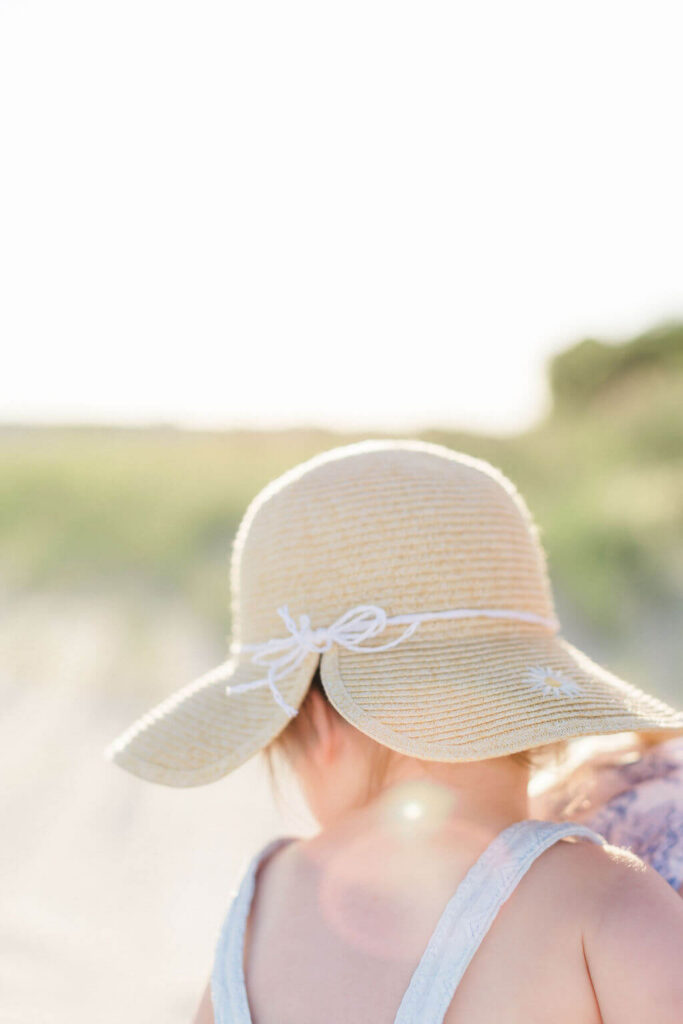 Mini Session, Half, or Full: Which Is Right for Your Family? (2026) Toddler in a straw sun hat with a white bow, looking out over the beach in golden hour light at the Jersey Shore