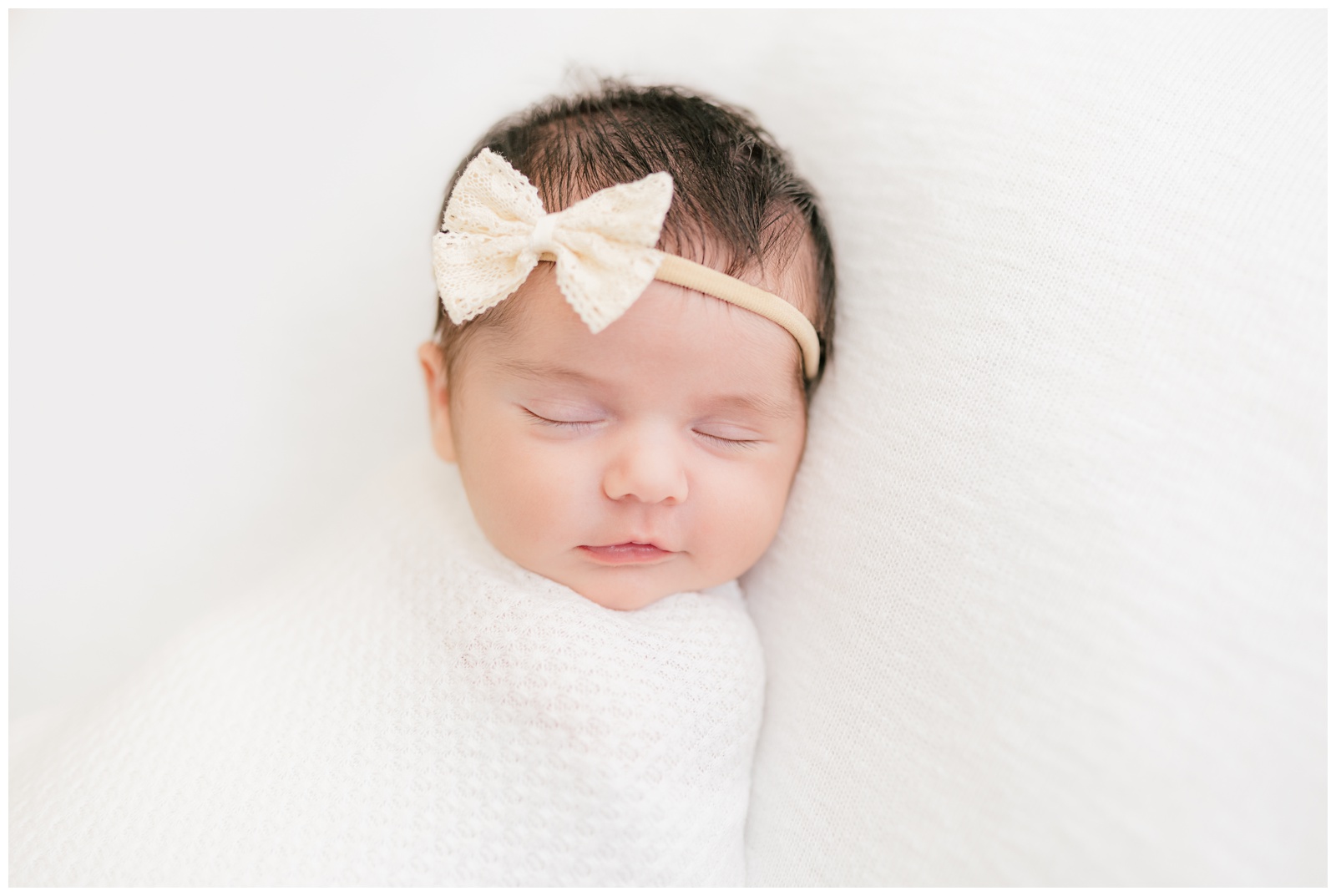 Portrait of sleeping baby with cream lace bow headband