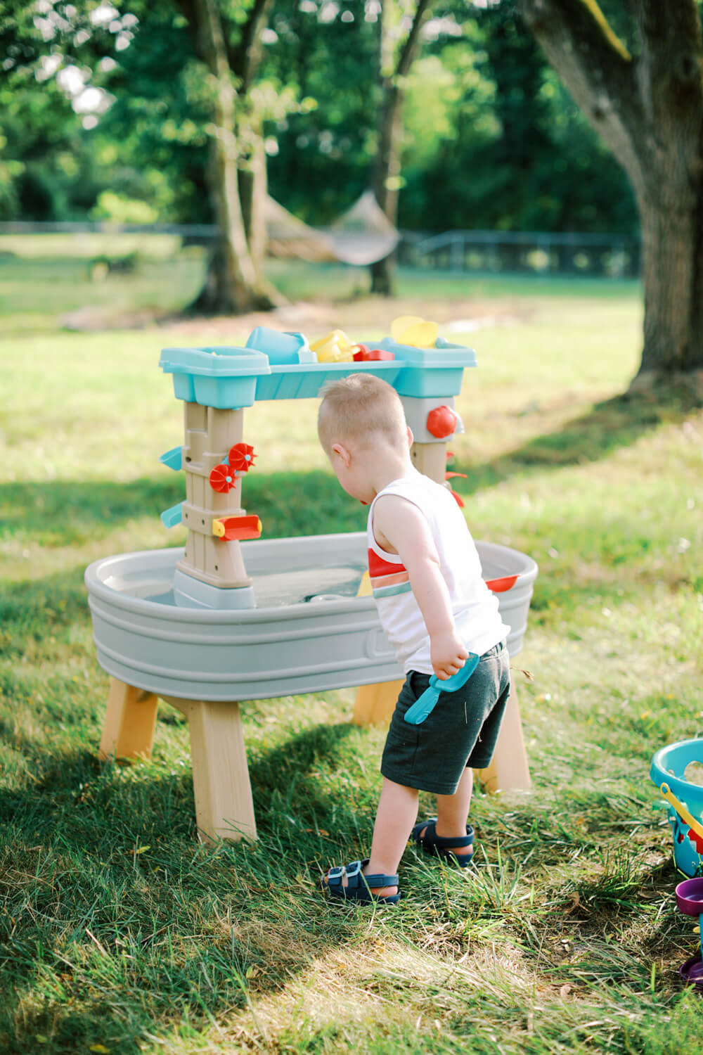 Toddler playing at water table in backyard on a sunny summer day