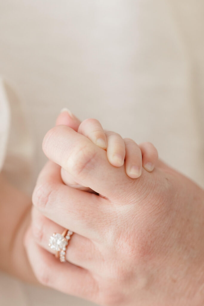 Choosing Privacy in the Age of AI Newborn baby's hand wrapped around parent's finger, faces intentionally not shown
