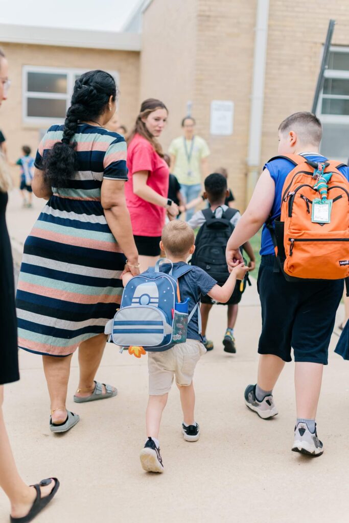 Your August Photo Scavenger Hunt Children and parents walking into school on the first day, backpacks on.
