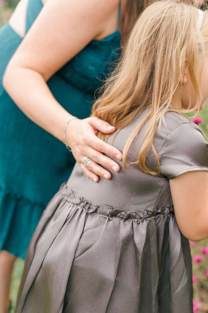 Beautiful Flower Farm Family Photos | Pretty Bird Farm, NJ Mom's hand resting on her daughter's back as they stand close together in the garden